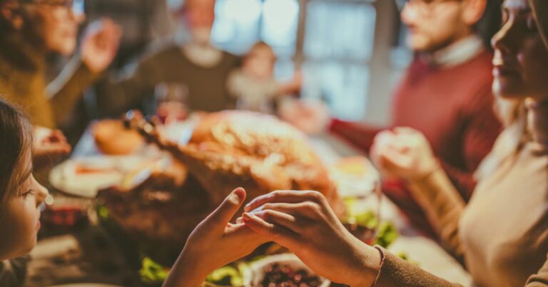 A warm and inviting Thanksgiving dinner scene with a family gathered around the table, sharing food and laughter. The table is set with a traditional Thanksgiving meal, including a roasted turkey, vegetables, and festive decor, creating a cozy and welcoming atmosphere.