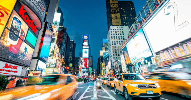 Busy New York City street scene with yellow cabs, pedestrians, and skyscrapers, illustrating the constant movement and urban environment that contributes to rapid dirt and grime buildup.